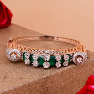 Elegant gold bangle with green gemstone accents and halo-set crystals on a beige background.