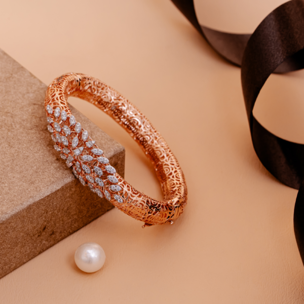 Lunaria Filigree Grace Bangle with intricate floral lattice and petal design on beige background.