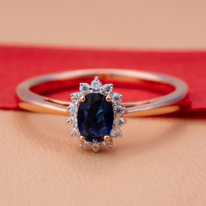 Elegant rose gold ring with an oval-cut deep blue sapphire centerpiece surrounded by a halo of white diamonds, reflecting classic sophistication